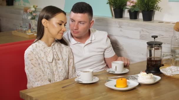 man kisses girl at date at table with tea and cakes in cafe - Footage, Video
