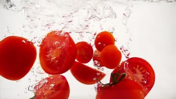 Las mitades cortadas de los tomates en el agua, primer plano en cámara lenta
 - Imágenes, Vídeo