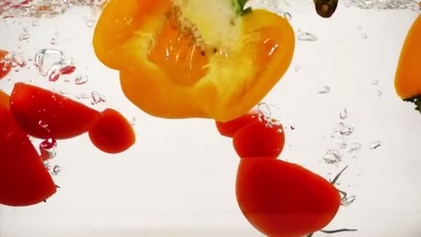 Biber ve domates sıçramaları ve kabarcıklar, yavaş hareket yakın çekim ile suya plop - Video, Çekim