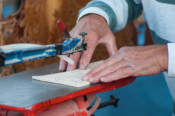Closeup of hands of old man working wood with metallic tool - Foto, imagen