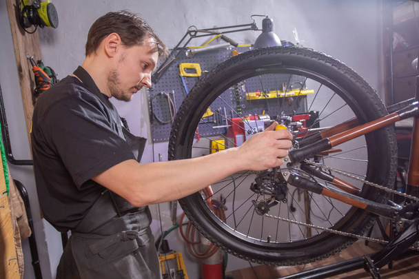 Service, reparatie, fiets en mensen concept-monteur repareren van een mountainbike in een workshop - Foto, afbeelding