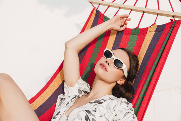 Serious young pretty woman at the beach posing on a hammock. - Фото, зображення