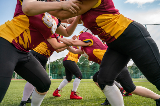 Foto van atleten vrouwen spelen American Football op groene gazon - Foto, afbeelding