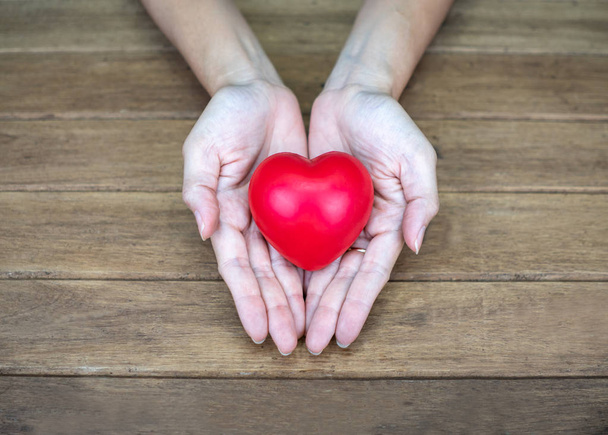 Hand holding Heart shape on wooden background - Photo, Image