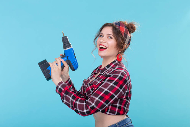 sexy junge Pin-up-Frau mit Drill über blauem Hintergrund - Foto, Bild