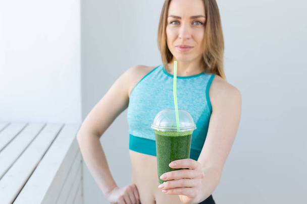 Healthy, sport, diet and people concept - Successful fitness urban woman recommending detox smoothie, close-up - Foto, Imagem