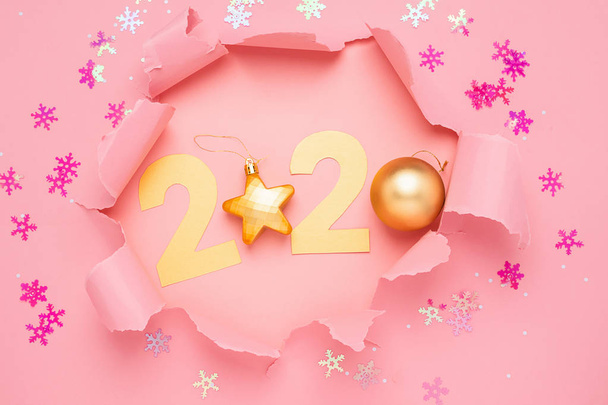 The symbol of the new year from the number 2020 and a hole on a pink paper background. Torn paper. New Year concept. - Photo, Image