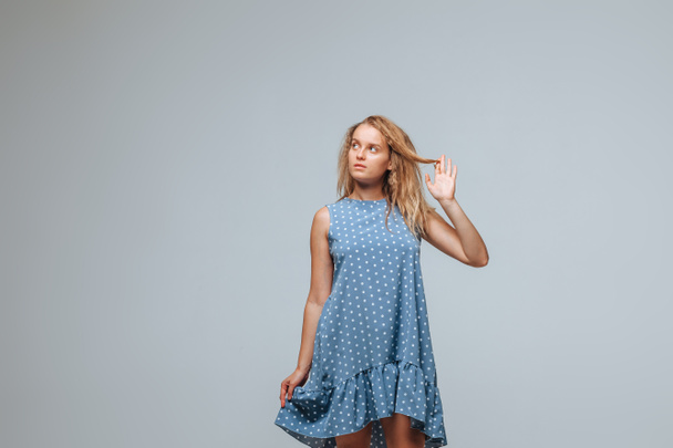 The girl wears a blue dress with peas on a light gray background - Photo, image