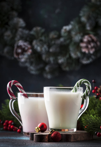Hot winter white drink with candy sticks, Christmas or New Year decorations, dark background, rustic style, copy space - Foto, Imagen