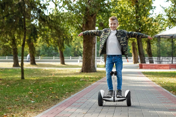 A boy riding a hoverboard in the park, a self-balancing scooter. Active lifestyle technology future - Fotó, kép