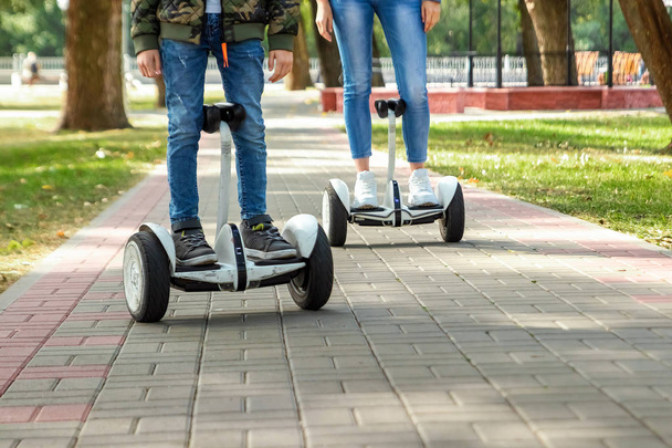 A young couple riding a hoverboard in a park, self-balancing scooter. Active lifestyle technology future - Фото, изображение