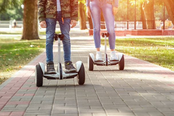 A young couple riding a hoverboard in a park, self-balancing scooter. Active lifestyle technology future - Zdjęcie, obraz