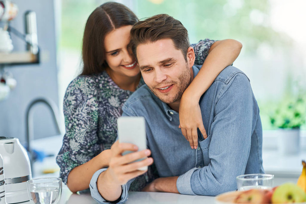 Couple in home kitchen using smartphone - Foto, Imagem