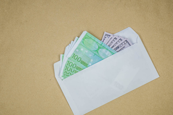 Empilement de dollars dans une enveloppe ouverte sur fond brun. Notion de corruption, profit illégal, racket
 - Photo, image