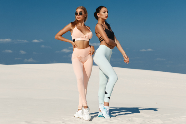 Beautiful fitness models in sportswear. Couple athletic girls in leggings outdoor - Foto, Imagem