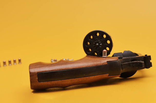 Gun with bullets on bright yellow background - Fotografie, Obrázek