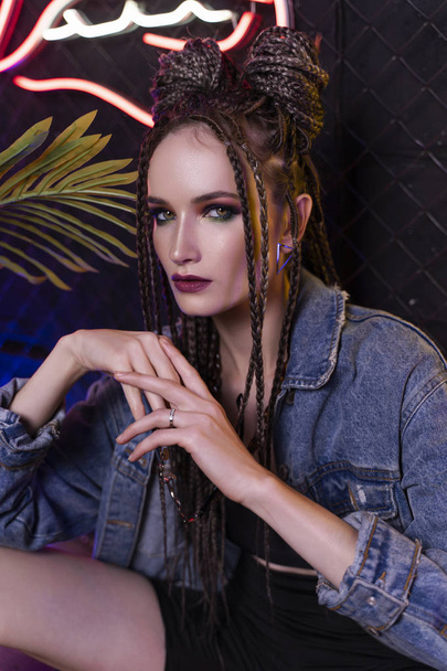 Beautiful girl with a afro cornrows, wearing denim jacket, sits  - Foto, Imagen