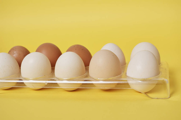 eggs in plastic container on bright yellow background - Fotó, kép