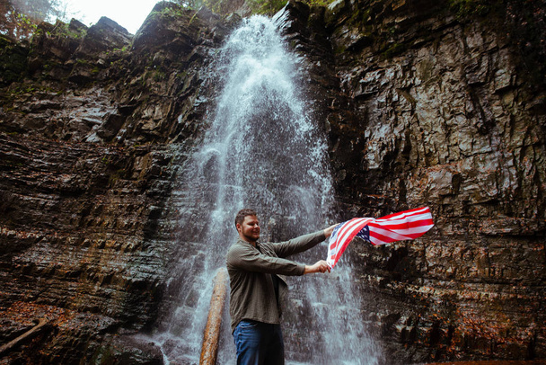 homem com EUA bandeira cachoeira no fundo
 - Foto, Imagem