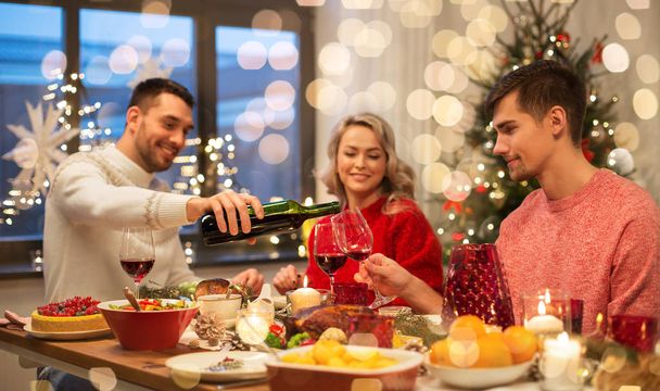 amis heureux boire du vin rouge à la fête de Noël - Photo, image