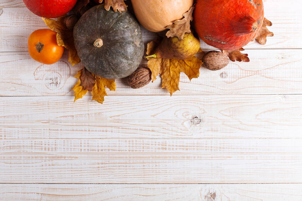 Different vegetables, pumpkins, apples, pears, nuts, tomatoes and dry leaves on a white wooden background. Autumn mood, copy space. Harvest concept. - Photo, image