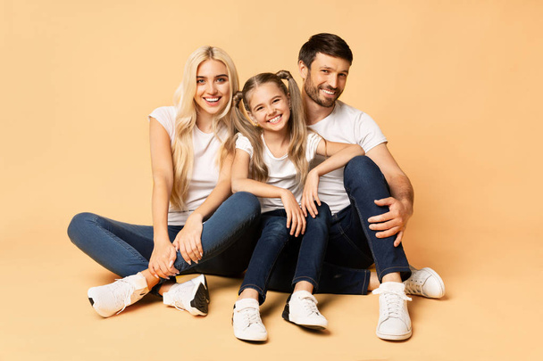 Happy Family Sitting Together Posing On Peach Background - Foto, Imagen