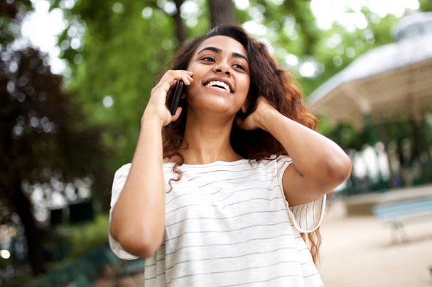 Close up portrait of young woman laughing and talking with mobile phone outdoors - Foto, Imagem