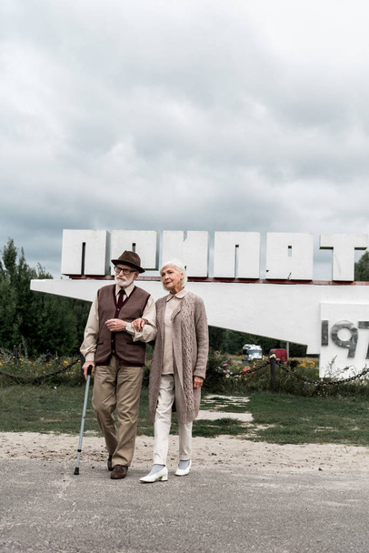 Pripjaty, Ukrajna-augusztus 15, 2019: nyugdíjas pár gyalogos közelében emlékmű a Pripjaty betűk - Fotó, kép