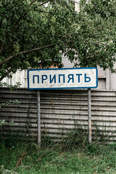 PRIPYAT, UKRAINE - AUGUST 15, 2019: sign with pripyat lettering near fence and trees  - Foto, Bild