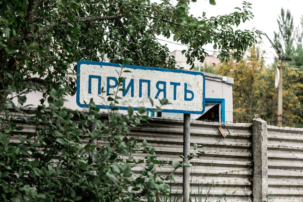 PRIPYAT, UKRAINE - AUGUST 15, 2019: sign with pripyat lettering near trees and fence - Valokuva, kuva