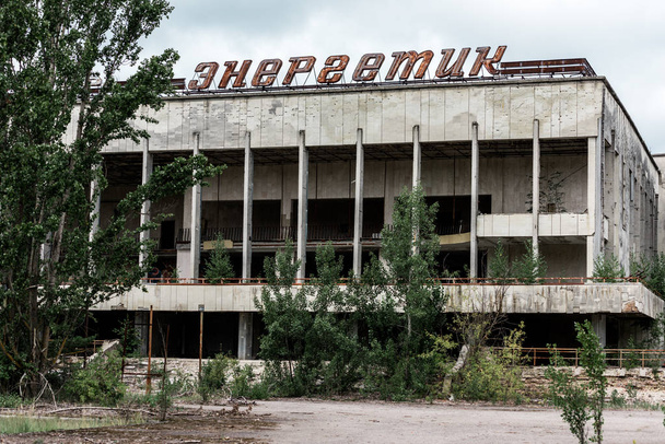 PRIPYAT, UKRAINE - AUGUST 15, 2019: building with energetic lettering near green trees in chernobyl  - Фото, изображение