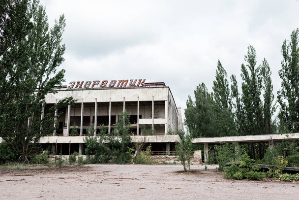 PRIPYAT, UKRAINE - AUGUST 15, 2019: building with energetic letters near green trees in chernobyl  - Фото, изображение