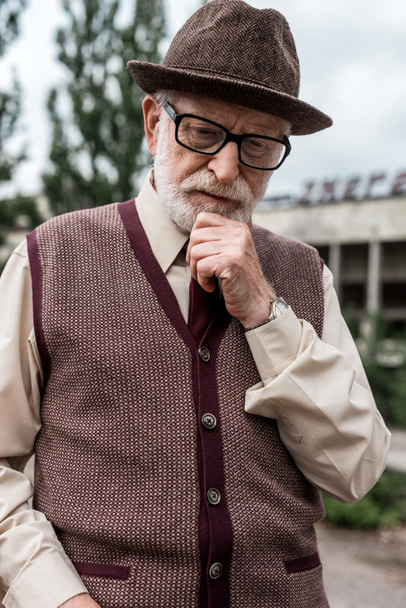 pensativo hombre mayor de pie cerca del edificio en chernobyl
  - Foto, Imagen