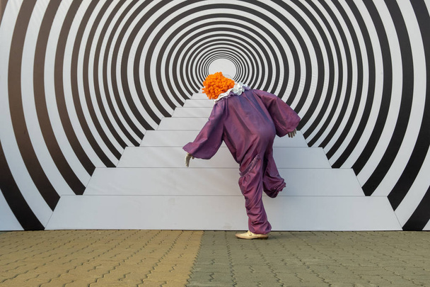 Egy férfi egy bohóc jelmezben úgy tesz, mintha lépcsőfokot. 3D kép az utcán formájában lépések és koncentrikus körök. Hipnotikus hatás és optikai csalódás. - Fotó, kép