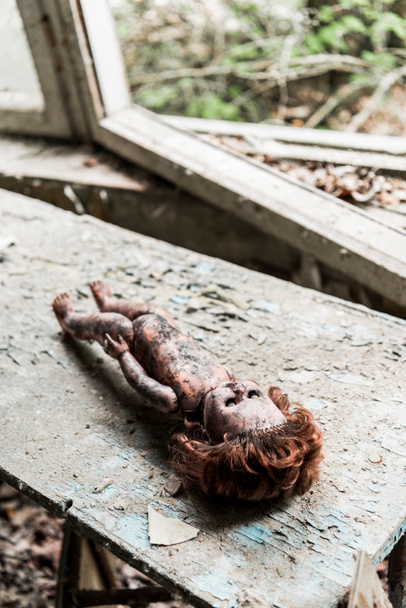 selective focus of creepy burnt baby doll on wooden damaged desk  - Photo, Image