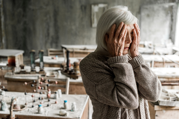 retired woman touching face and standing in dirty classroom  - Photo, Image