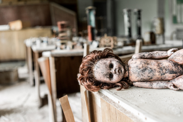 selektivní zaměření strašidelné dětské panenky na dřevěném stole ve třídě  - Fotografie, Obrázek