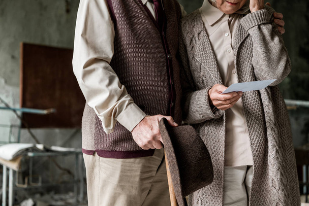 cropped view of retired couple standing in abandoned school and holding photo  - Photo, Image