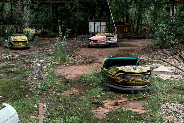 PRIPYAT, UKRAINE - AUGUST 15, 2019: selective focus of abandoned bumper cars in amusement park  - Photo, Image