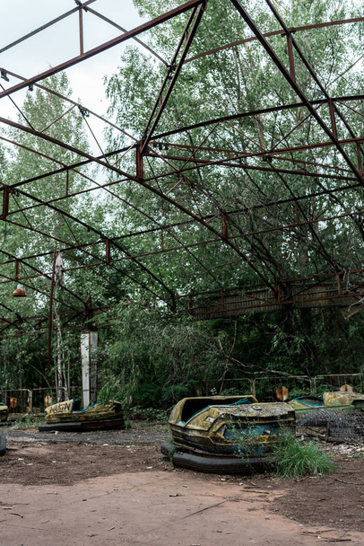PRIPYAT, UKRAINE - AUGUST 15, 2019: dirty and abandoned bumper cars in amusement park  - Zdjęcie, obraz