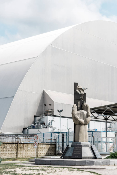 PRIPYAT, UKRAINE - AUGUST 15, 2019: concrete monument near abandoned chernobyl reactor against blue sky with clouds  - Fotó, kép