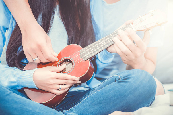 Young Asian couple playing ukulele relaxing with happiness and j - Photo, Image
