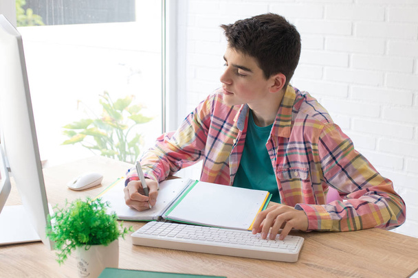 молодий студент з комп'ютером на домашньому столі або школі
 - Фото, зображення