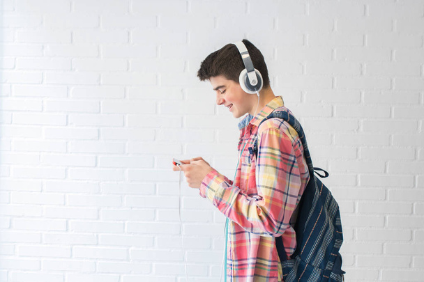 étudiant avec sac à dos, téléphone portable et écouteurs écoutant de la musique
 - Photo, image