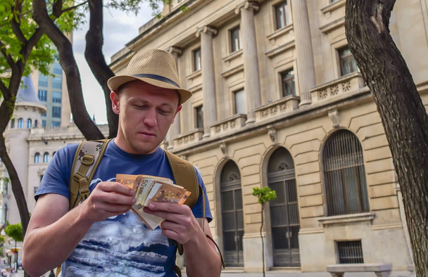 若い男性観光客は、ヨーロッパの都市の路上で現金を数えます - 写真・画像