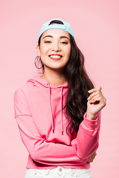 attrayant asiatique femme en rose pullover et chapeau sourire isolé sur rose
  - Photo, image