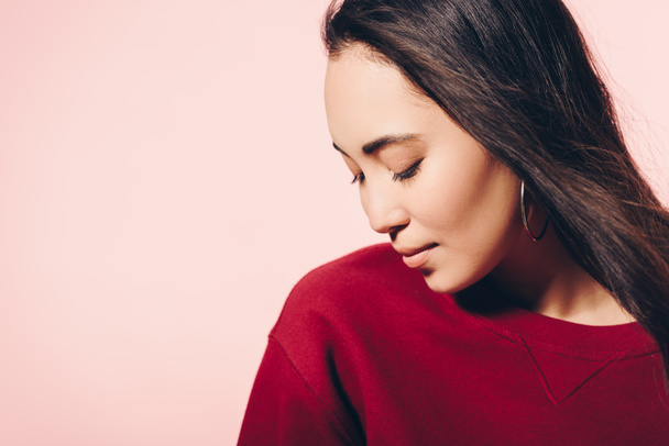 attractive asian woman in red sweater with closed eyes isolated on pink  - Photo, Image