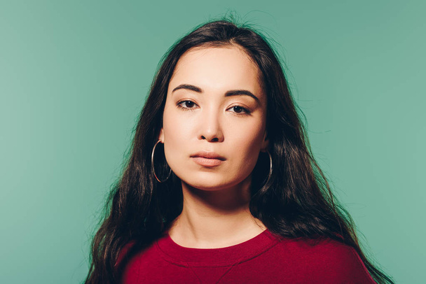 attractive asian woman in red sweater looking at camera isolated on green   - Φωτογραφία, εικόνα