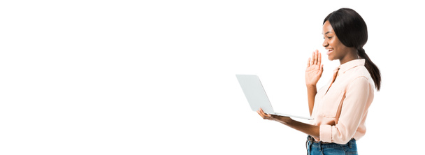 plan panoramique de femme afro-américaine en chemise tenant un ordinateur portable et parlant dans le chat vidéo isolé sur blanc
  - Photo, image