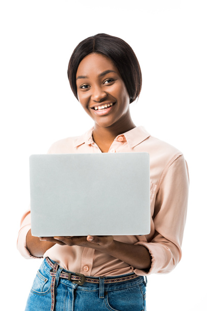 χαμογελαστή Αφροαμερικανή γυναίκα με πουκάμισο που κρατά φορητό υπολογιστή απομονωμένο σε λευκό  - Φωτογραφία, εικόνα